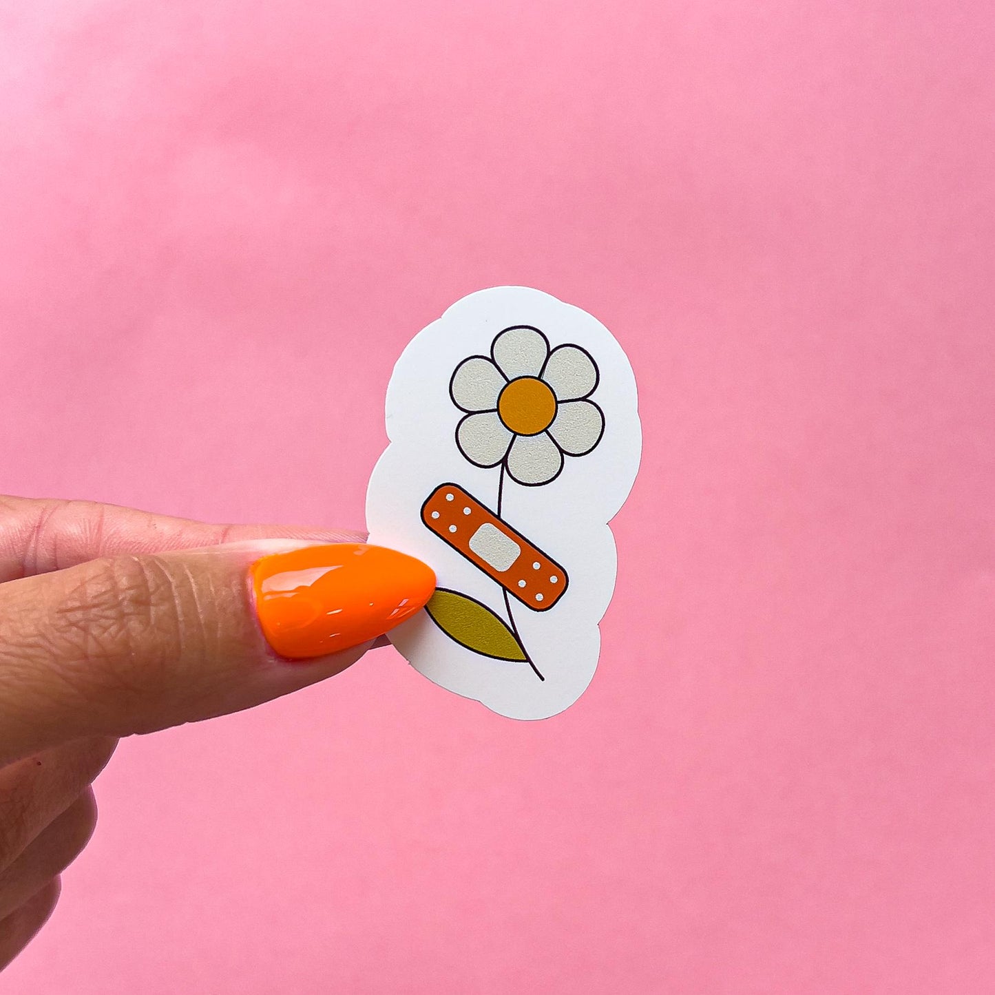 A vinyl decal sticker of a white daisy with an orange center and a brown band-aid bandage on the stem.