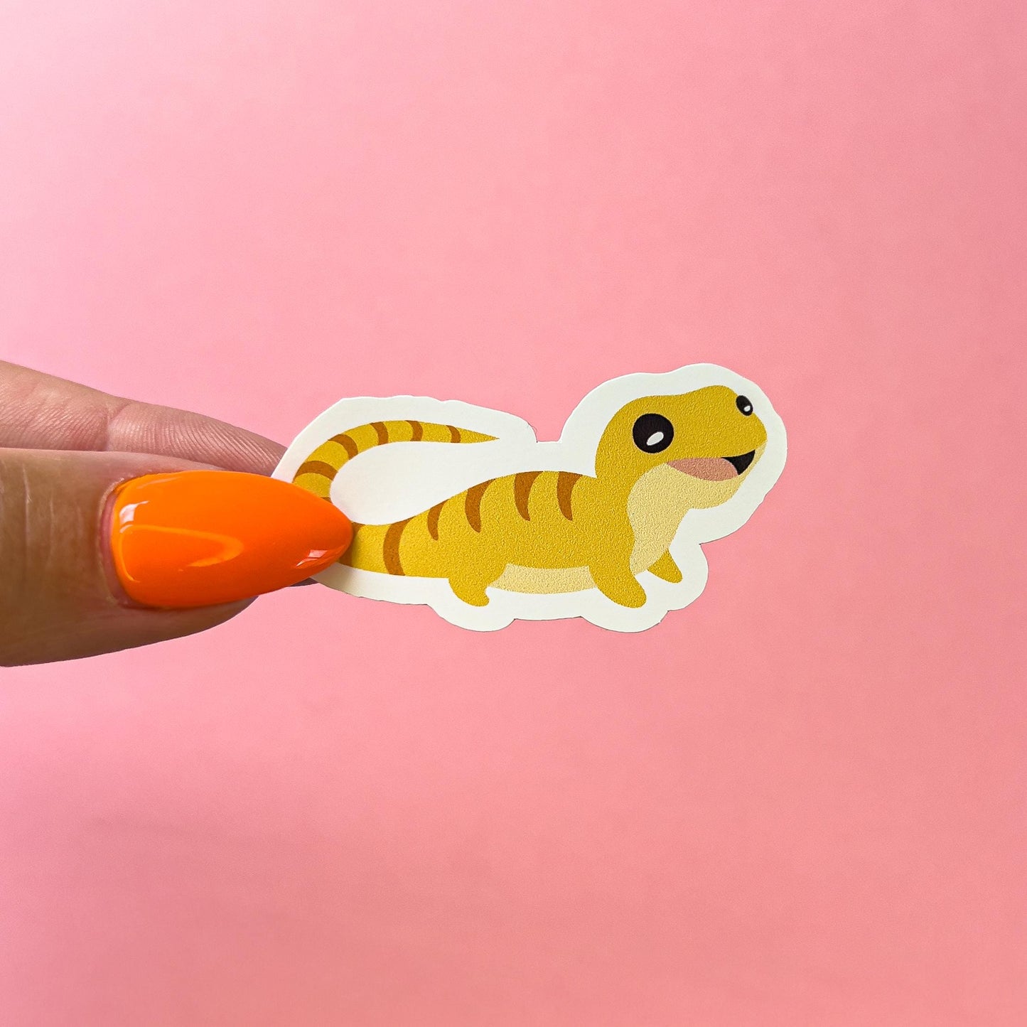 A vinyl decal sticker of a smiling, yellow gecko with orange stripes.