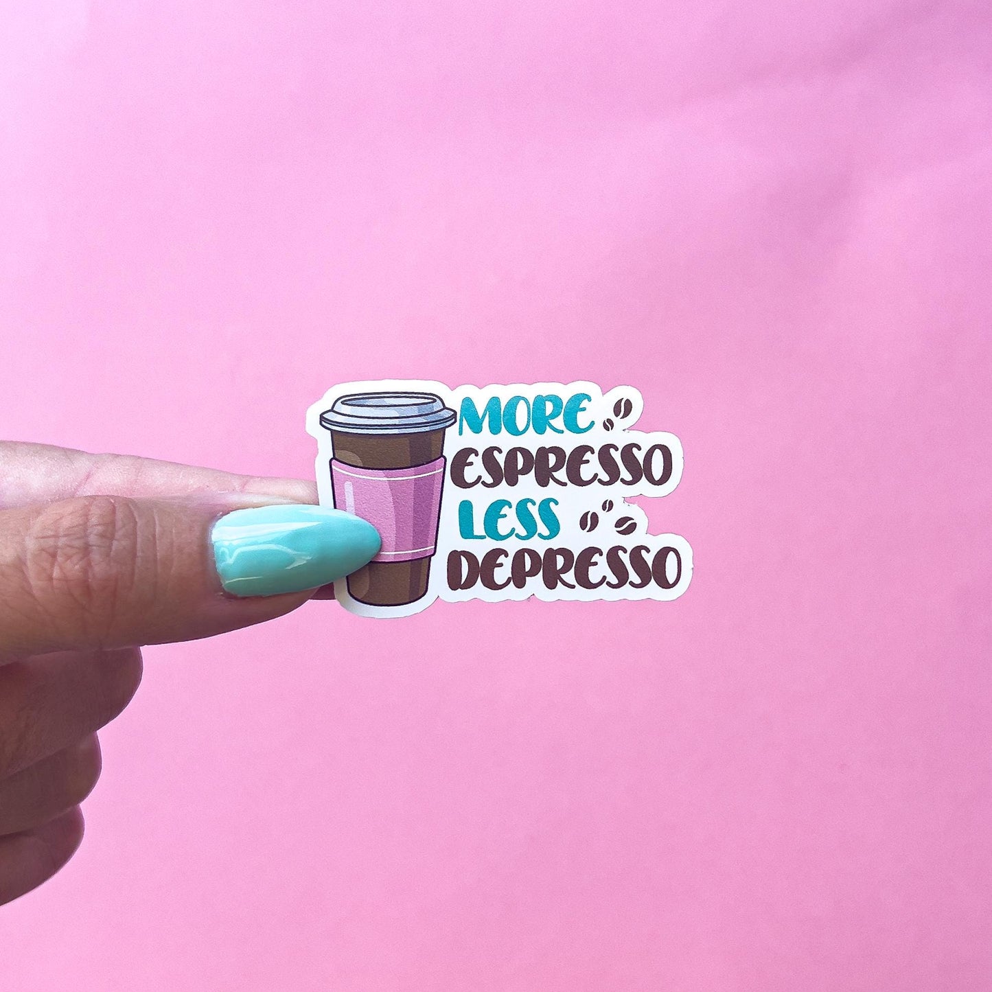A vinyl decal sticker of a brown, pink and white hot coffee to go cup. the text is brown and teal and reads “more espresso less depresso”