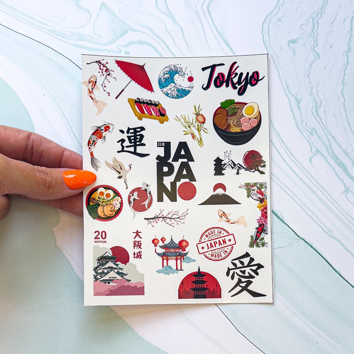 A sheet of Japanese themes stickers. The stickers include koi fish, ramen, an umbrella, "TOKYO" in black and read styled font, Japanese characters, sushi, a stamp, "JAPAN" in black and red styled font, cherry blossoms, temples, ect.