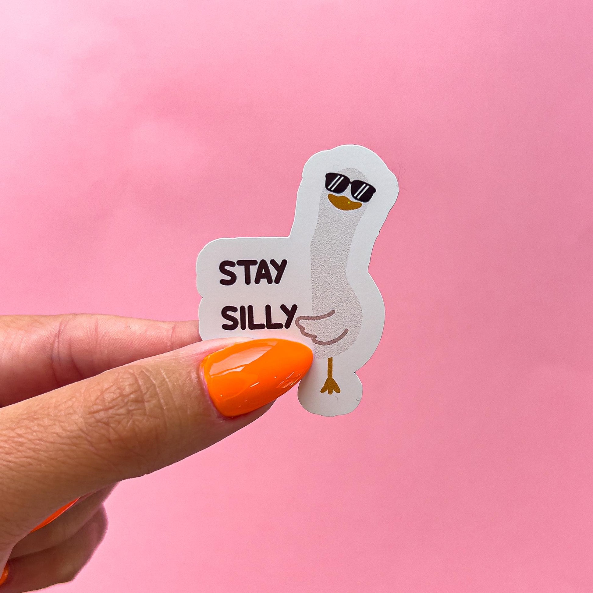 A vinyl decal sticker of a white goose wearing sunglasses peeking around the text 'STAY SILLY' in black.