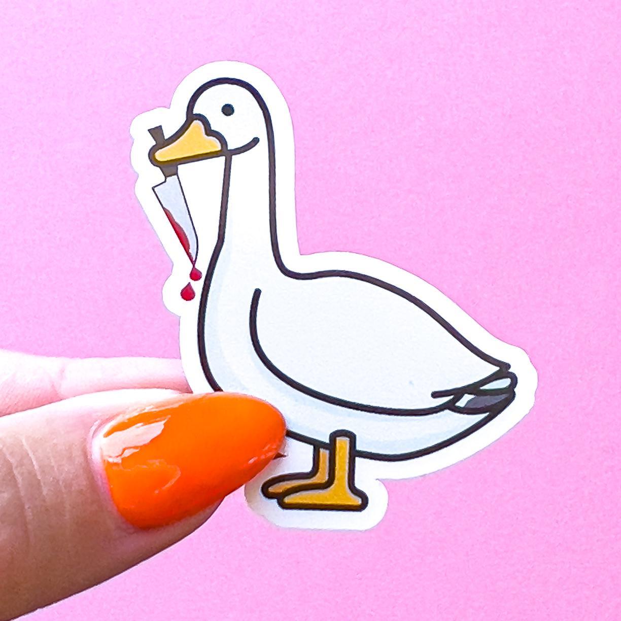 A white goose/duck sticker with a black outline holding a bloody tipped knife in its beak. The goose/duck has yellow feet and beak.