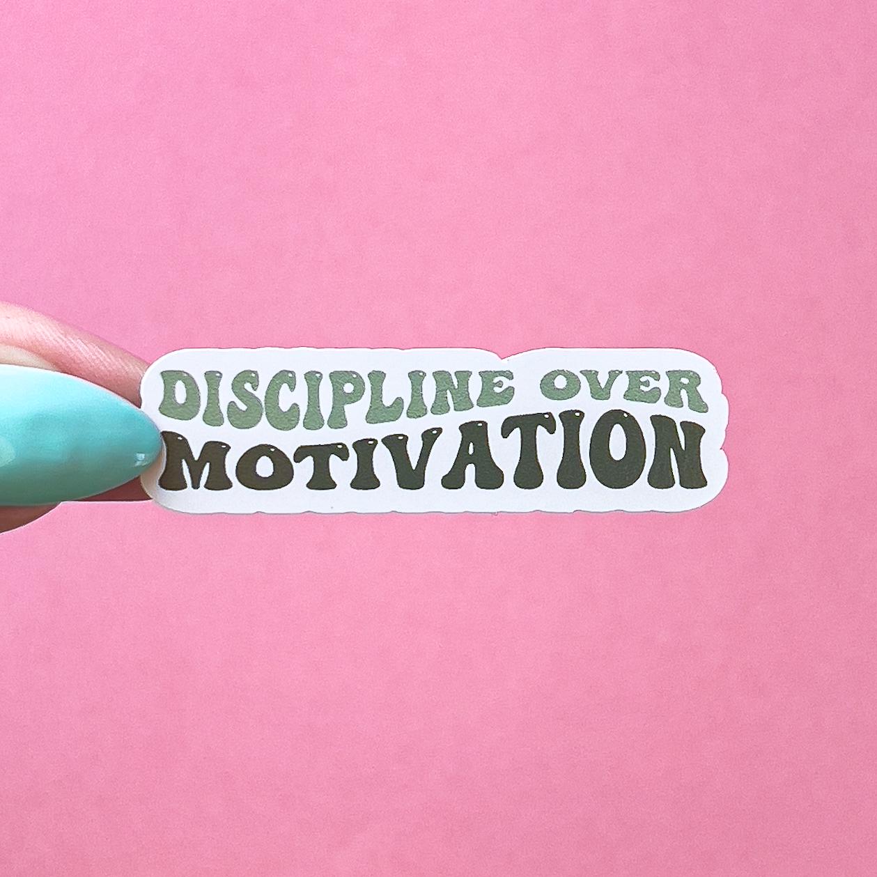 A vinyl decal sticker with light and dark green text that reads "DISCIPLINE OVER MOTIVATION" in a bubbly text.