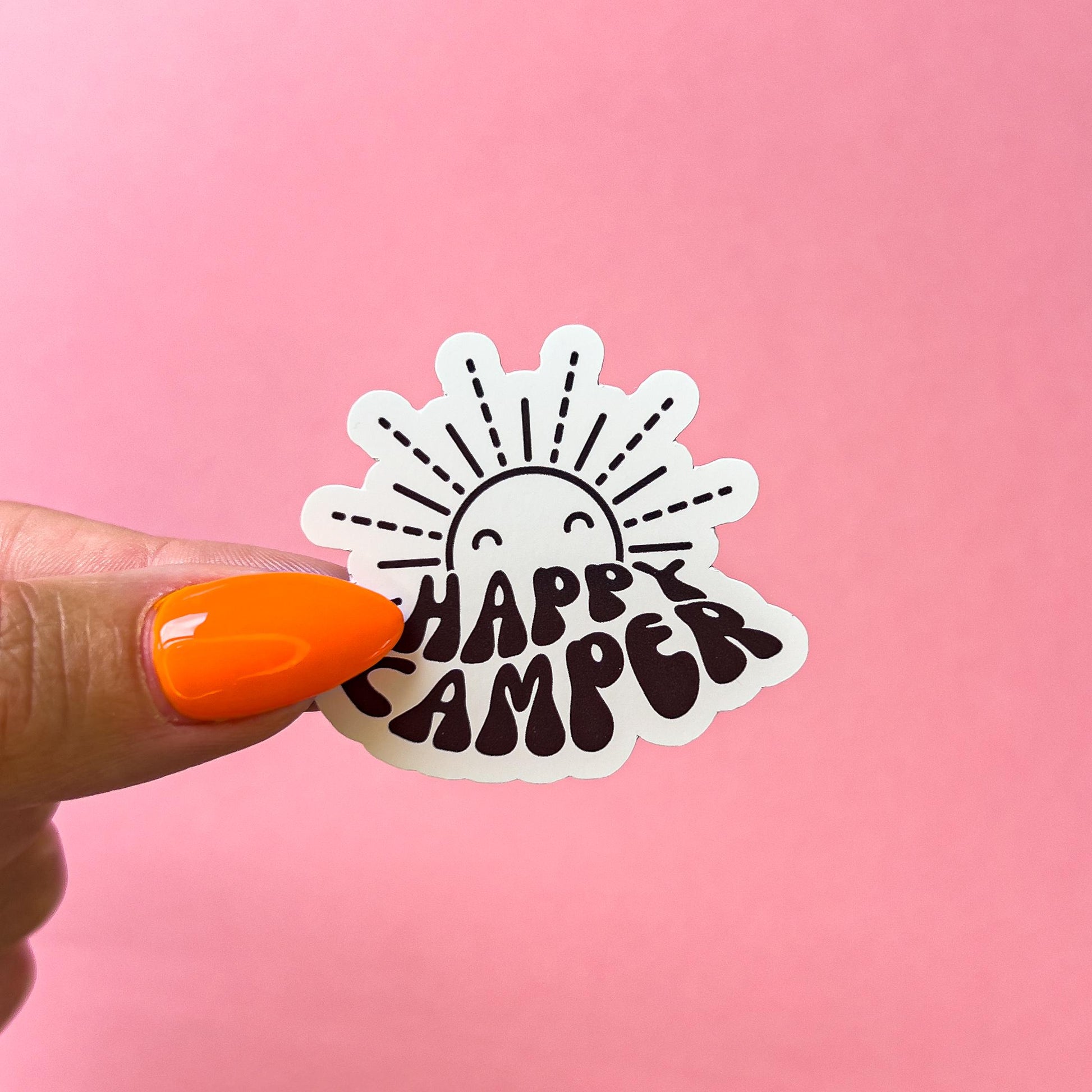 A vinyl decal sticker with a smiling black outline sun and the text 'HAPPY CAMPER' in a wavy font.