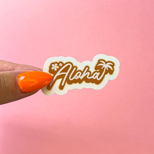 A vinyl decal sticker of orange cursive word 'Aloha' with a small flower and palm tree design.