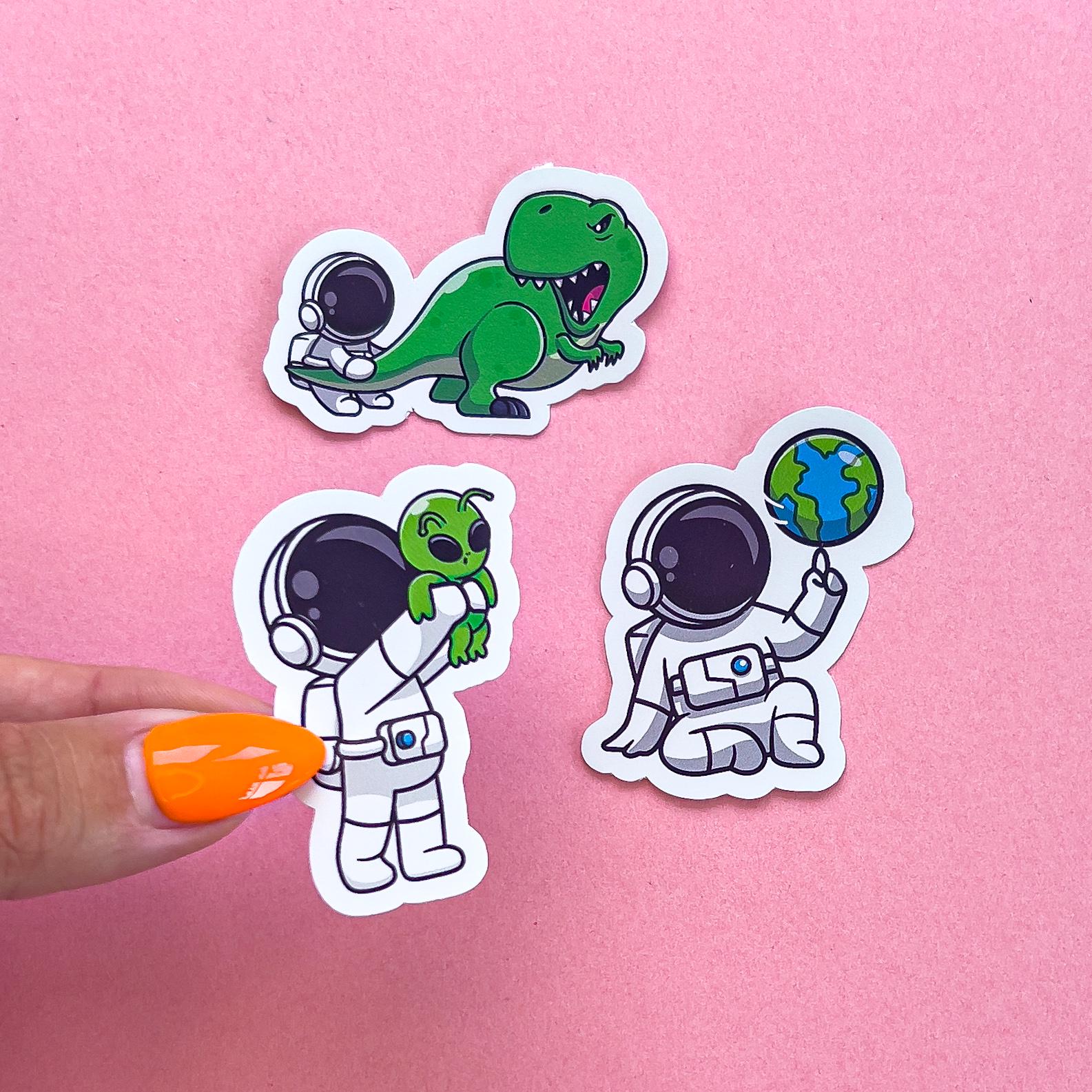 Three vinyl decal stickers of astronauts in various poses.