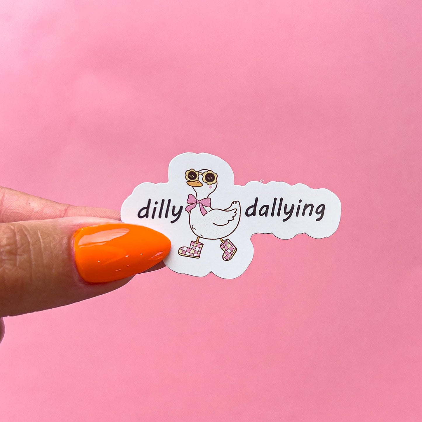 A vinyl decal sticker of a white goose/duck wearing yellow sunglasses and a pink bow tie, walking in pink and white checkered boots. The goose is in a walking pose. The words 'dilly dallying' on either side of the goose.