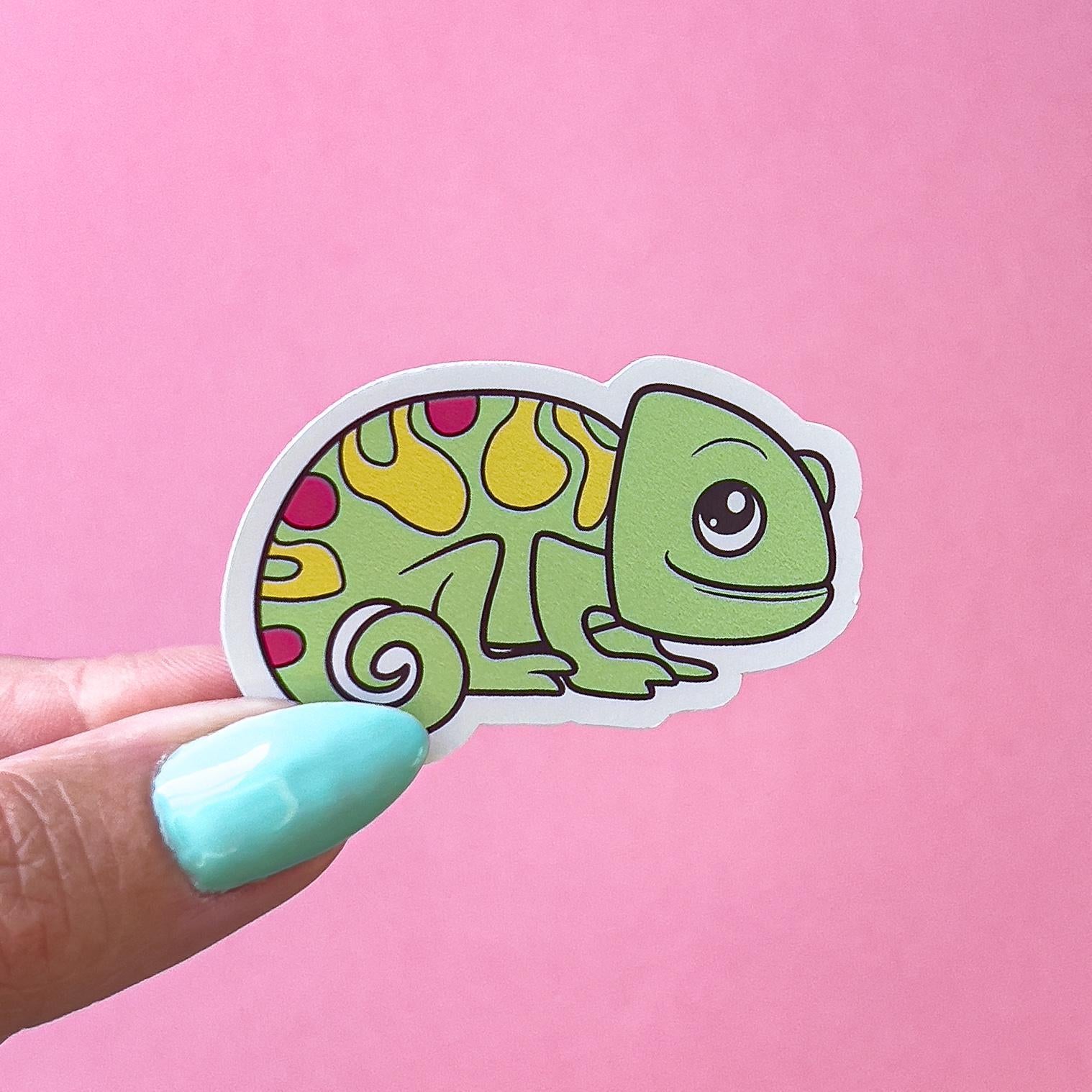 A vinyl decal sticker of a green chameleon sticker with yellow and pink spots. The chameleon has a big, round eye and a friendly smile.