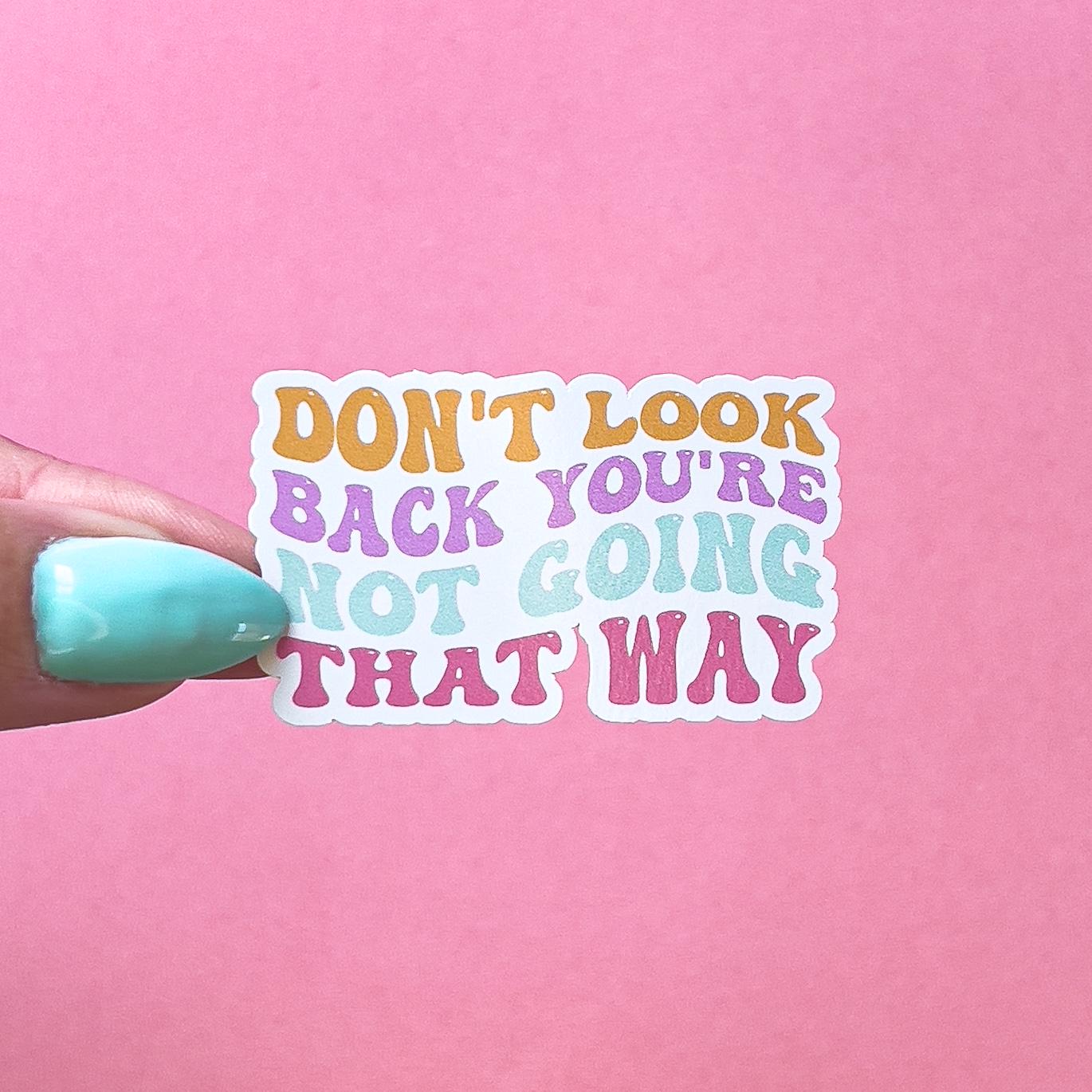 A vinyl decal sticker with the text "Don't look back you're not going that way" in rainbow stylized font. The text is orange, pink, purple, and blue.