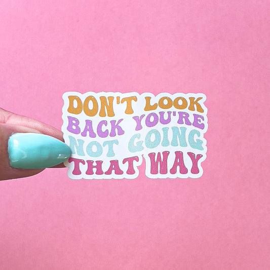 A vinyl decal sticker with the text "Don't look back you're not going that way" in rainbow stylized font. The text is orange, pink, purple, and blue.