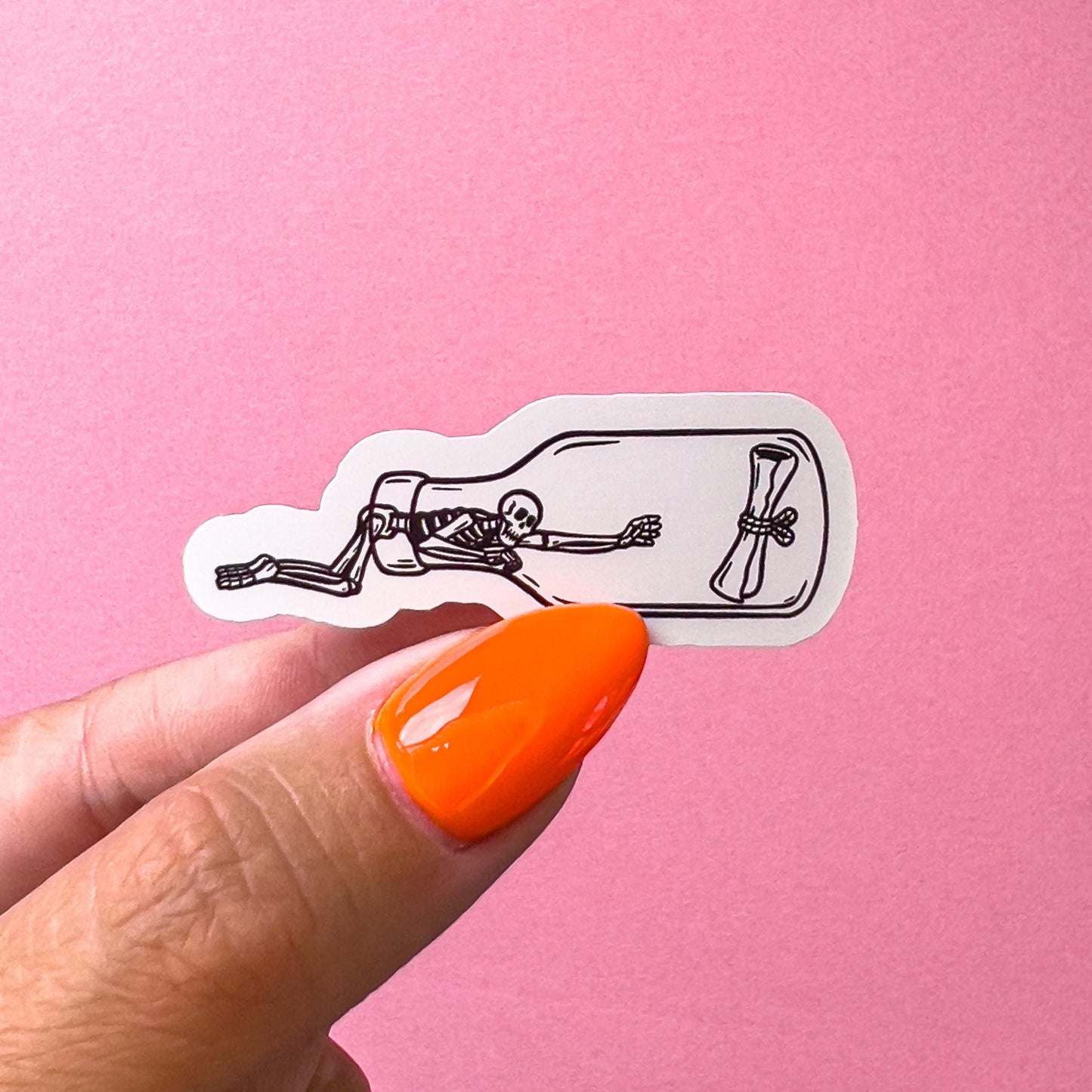 A vinyl decal sticker of a skeleton crawling into a glass bottle to grab a letter.
