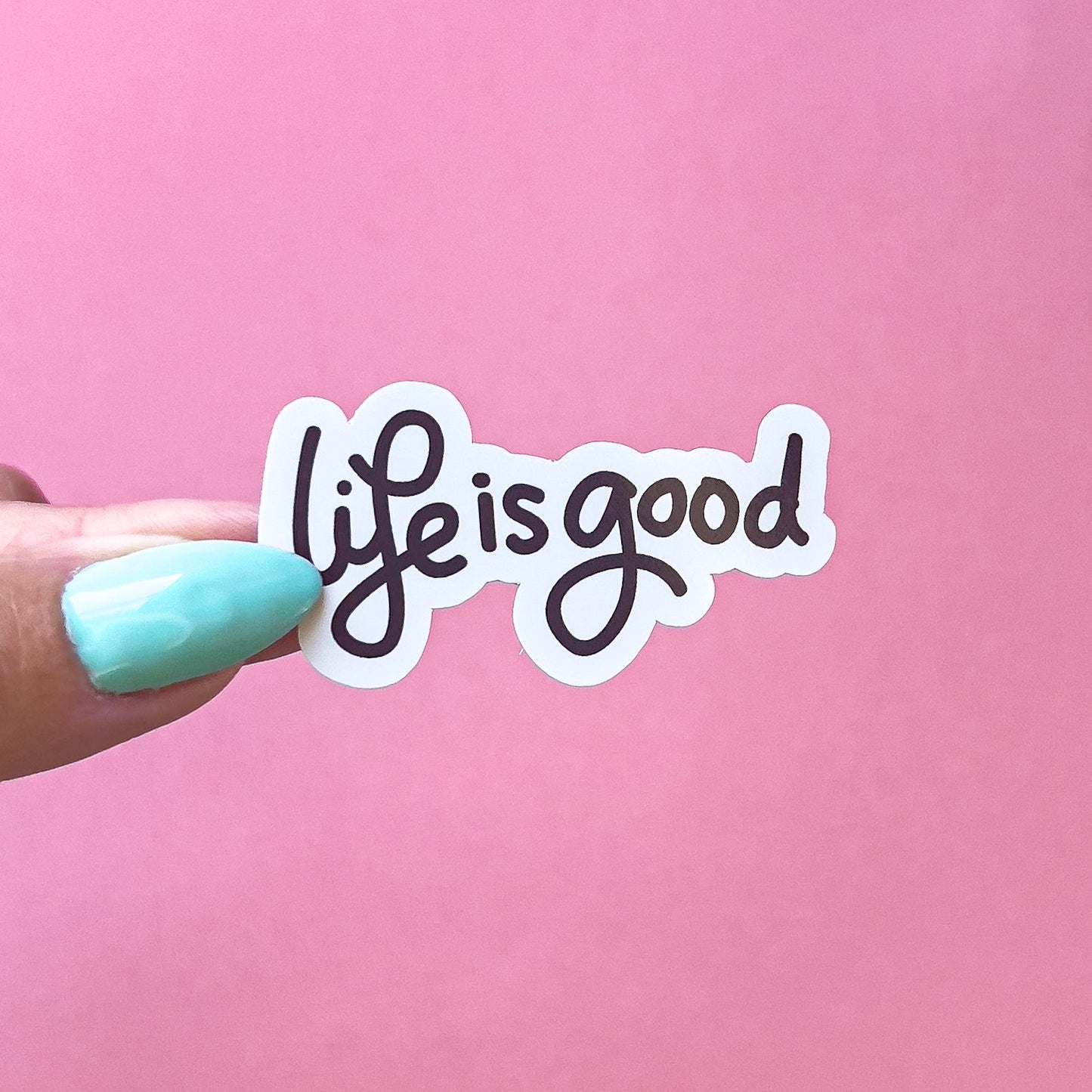 A vinyl decal sticker with black cursive text that reads 'life is good'.