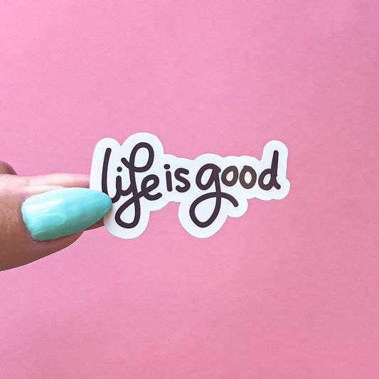 A vinyl decal sticker with black cursive text that reads 'life is good'.
