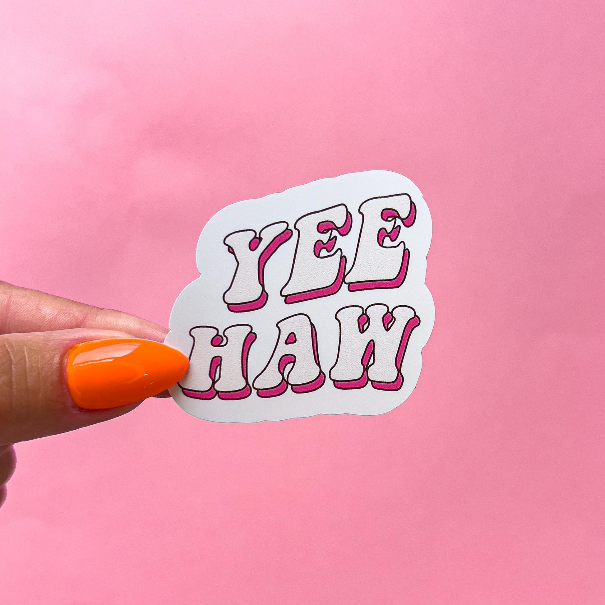A vinyl decal sticker with pink shadowed beige lettering that reads 'YEE HAW' in a retro font style.