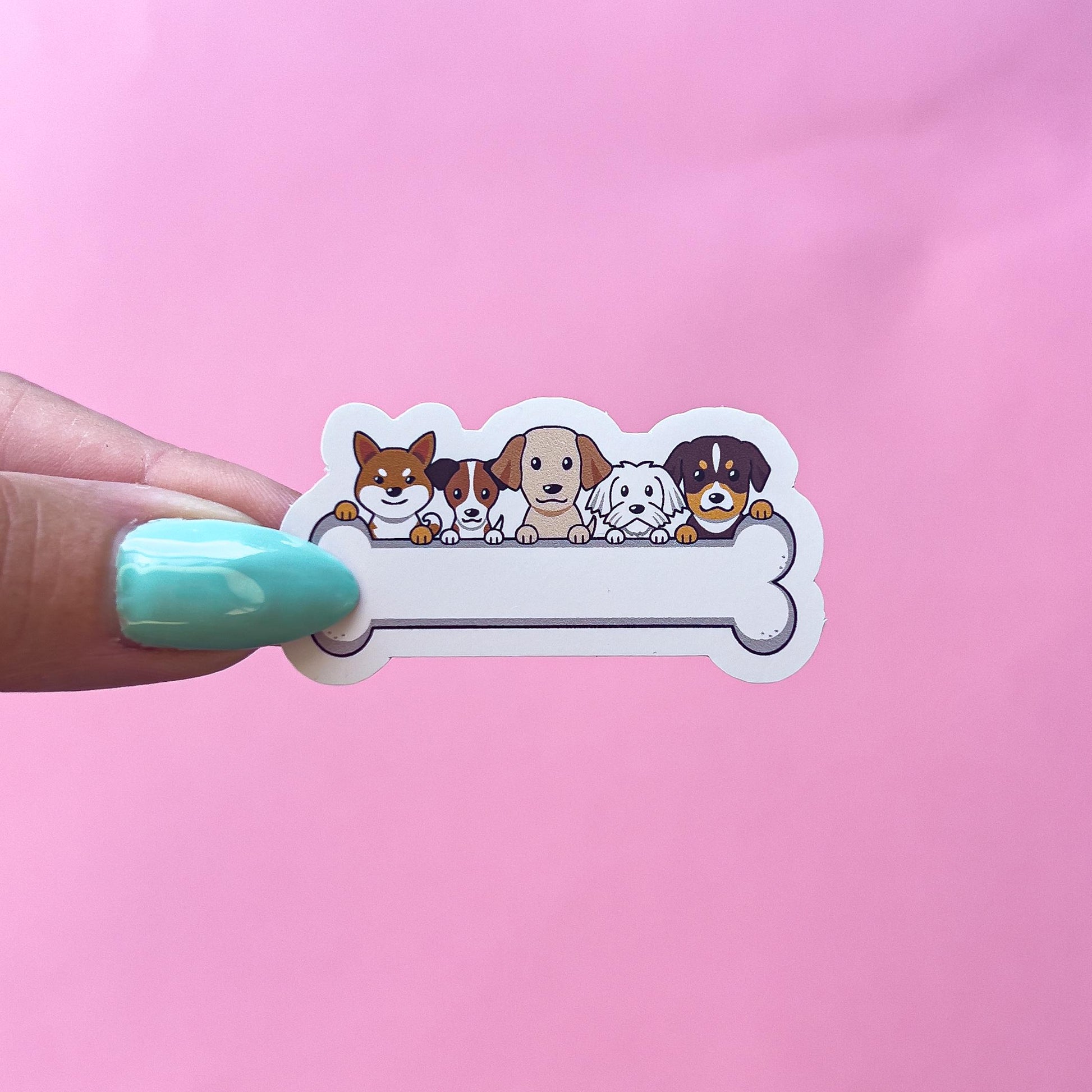 A vinyl decal sticker of a white bone with five cartoon dogs peeking over the top. The dogs are different breeds and colored brown, beige and white.