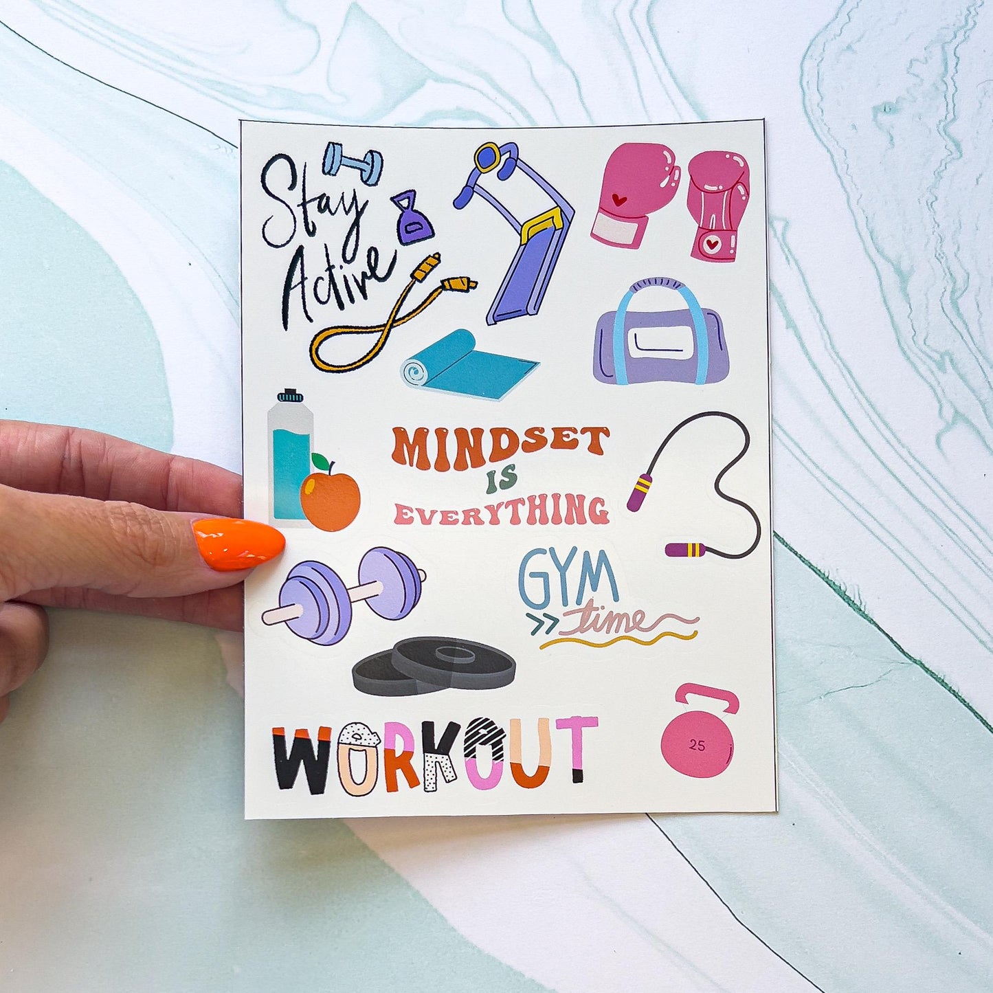 A gym/exercise themed sticker sheet. One sticker reads "Mindset over Everything" in wavy, orange and pink text. Another says "WORKOUT" in multiple colors and patterns.  The stickers include pink boxing gloves, lavender dumbbell, a water bottle and orange, a pink kettlebell, a jump rope, blue treadmill, and purple and a blue gym bag.