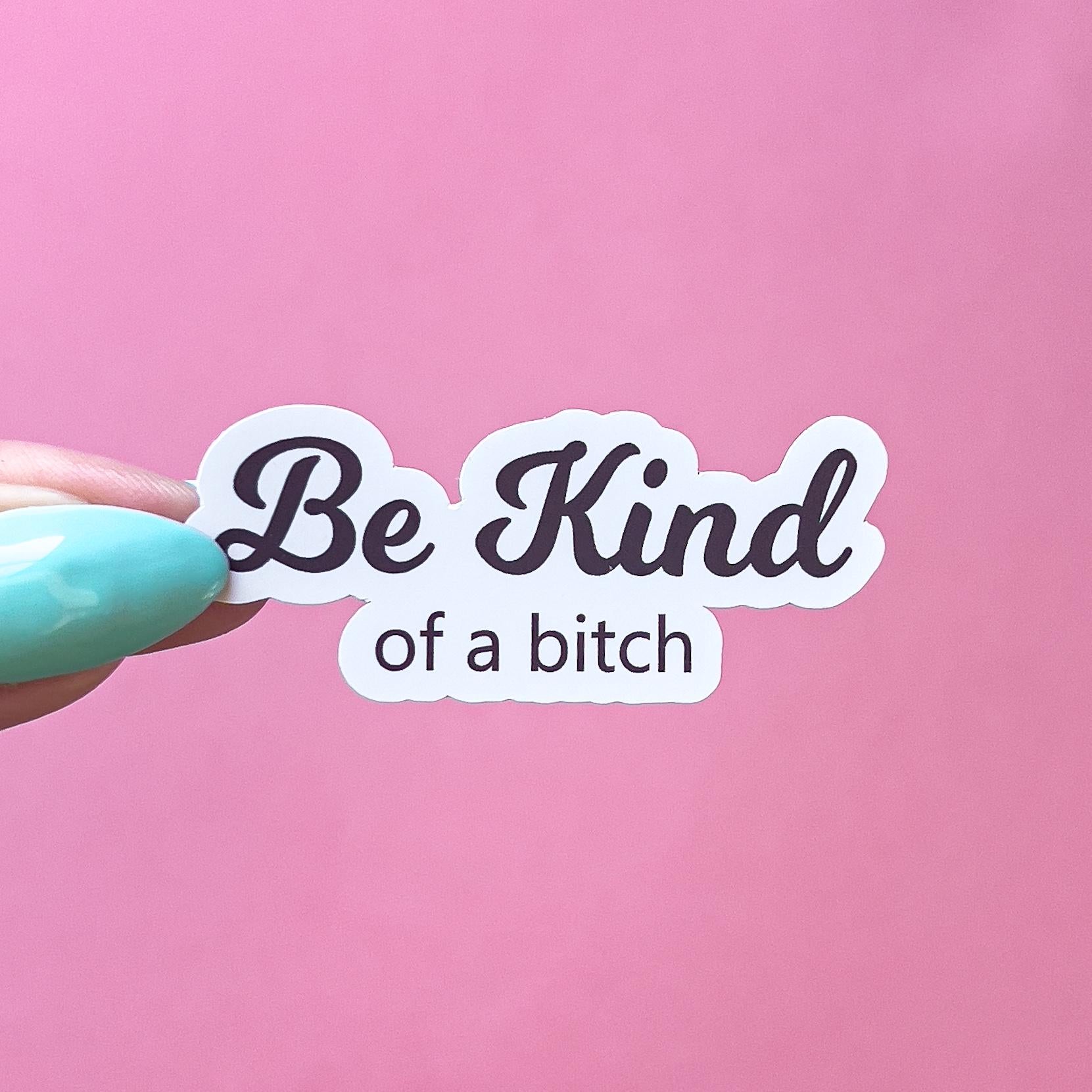A vinyl decal sticker with black text that reads "Be Kind" in large cursive text. Underneath small, black text reads "of a bitch"