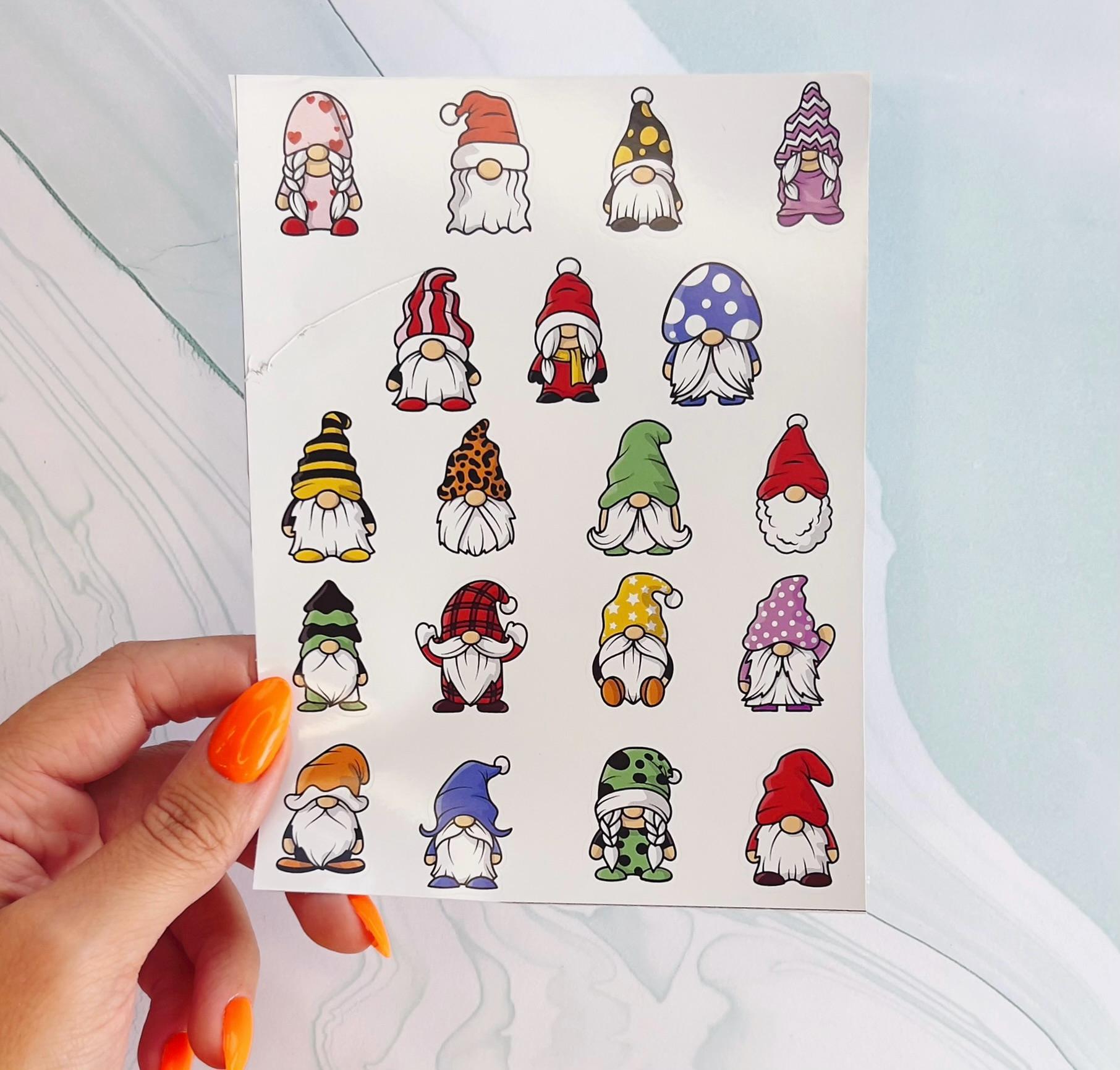 A sheet of stickers with 18 different gnomes. The gnomes are all wearing different colored hats and clothing. The gnomes are all smiling and have white beards. The gnomes are all different sizes and shapes.