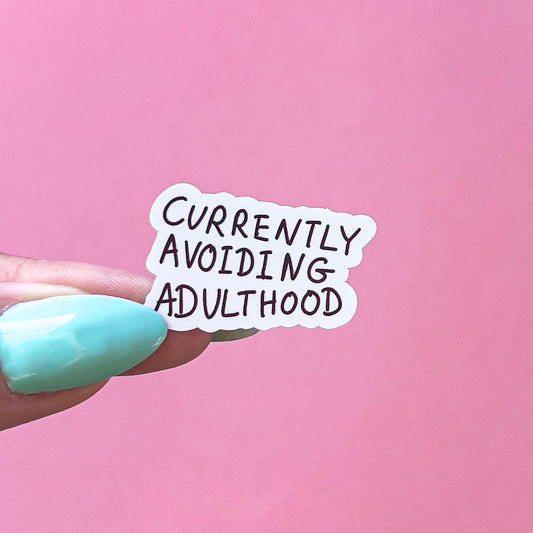 A vinyl decal sticker with black text that reads 'Currently Avoiding Adulthood'.