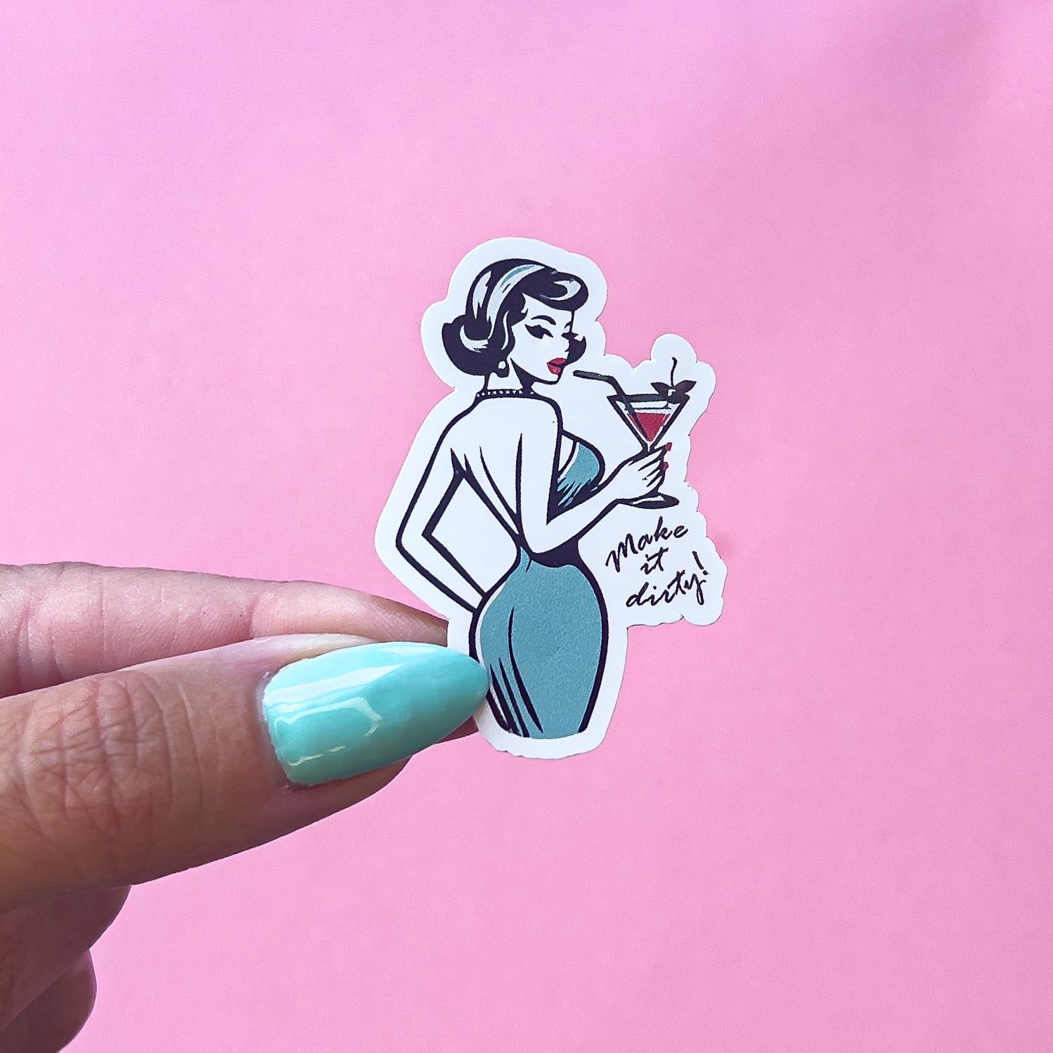 A vinyl decal sticker of a vintage, pinup woman in a blue dress holding a martini cocktail glass. The text on the sticker reads 'Make it dirty!'