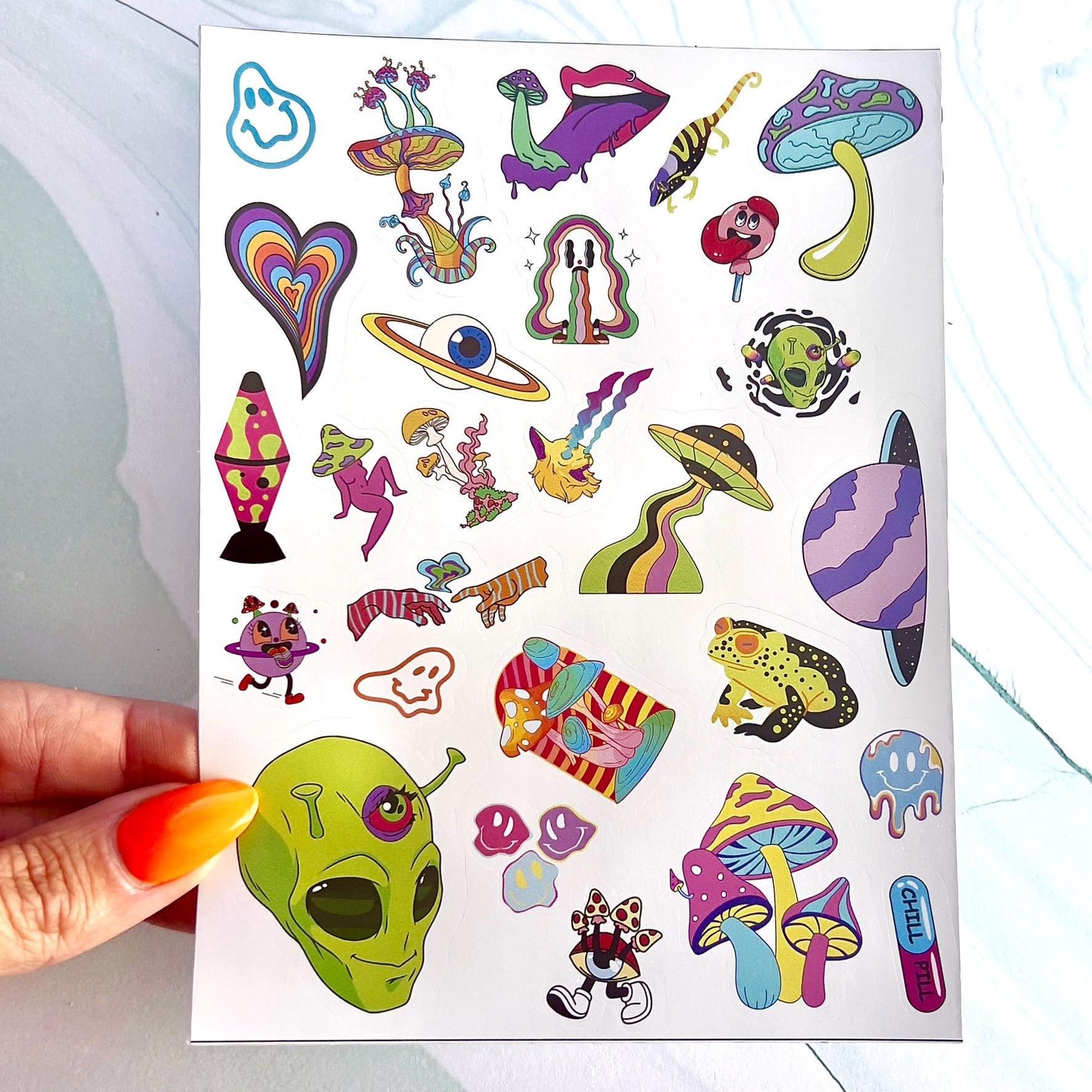 A sheet of colorful stickers with a variety of designs including mushrooms, aliens, eyes, hearts, and a lava lamp. The stickers have a psychedelic theme with various colors including bright green, yellow, light blue, orange, yellow, purple, and red. One sticker reads 'Chill Pill'.
