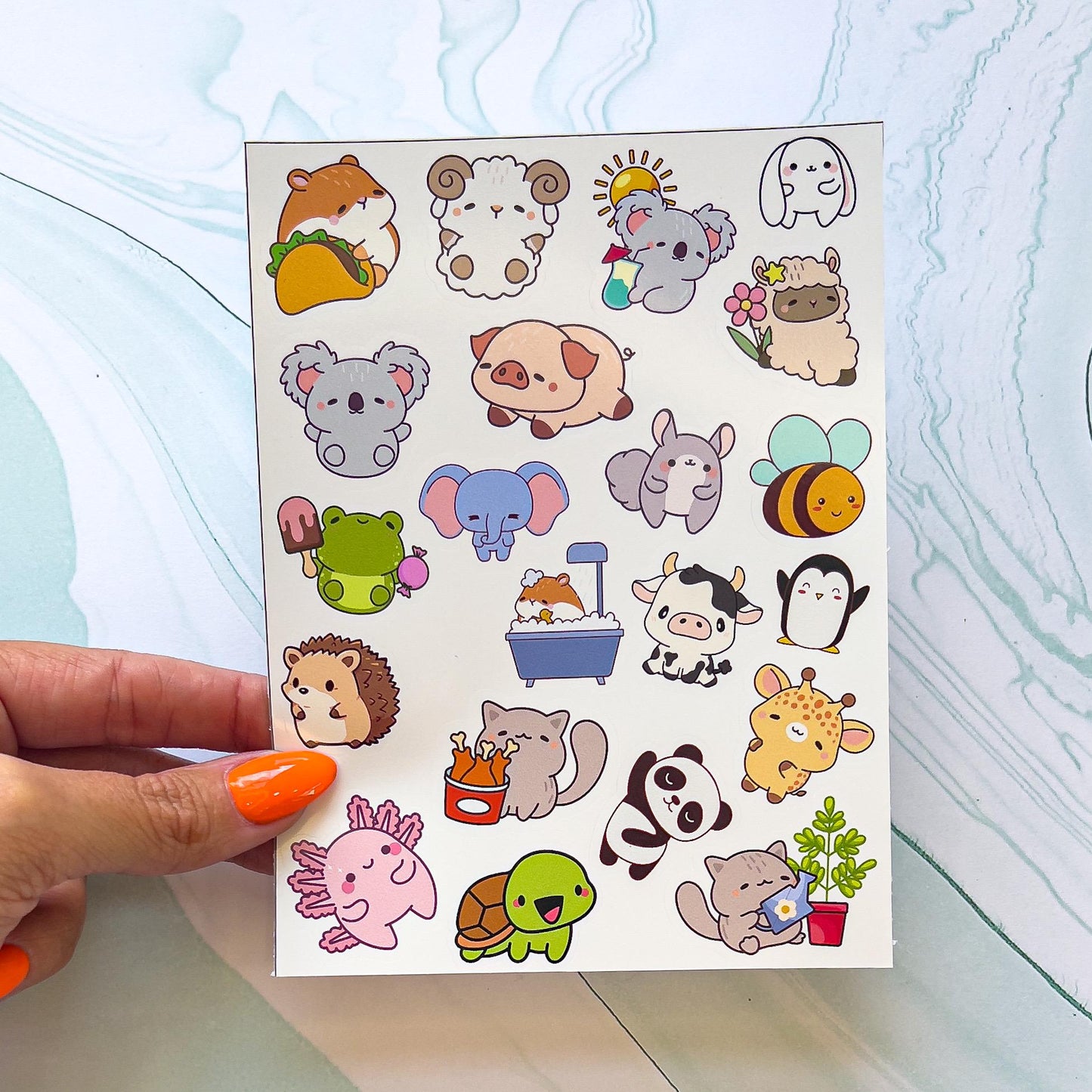 A sheet of various cartoon kawaii style animal stickers. The stickers include a hamster with a taco, an elephant, hedgehog, a frog with ice cream, a turtle, penguin, bee, a koala with drink, a hamster in a  bathtub, a cat watering a plant, a sheep with a flower, a cat with a bucket of chicken, a panda, a salamander, a squirrel, a cow, ect.