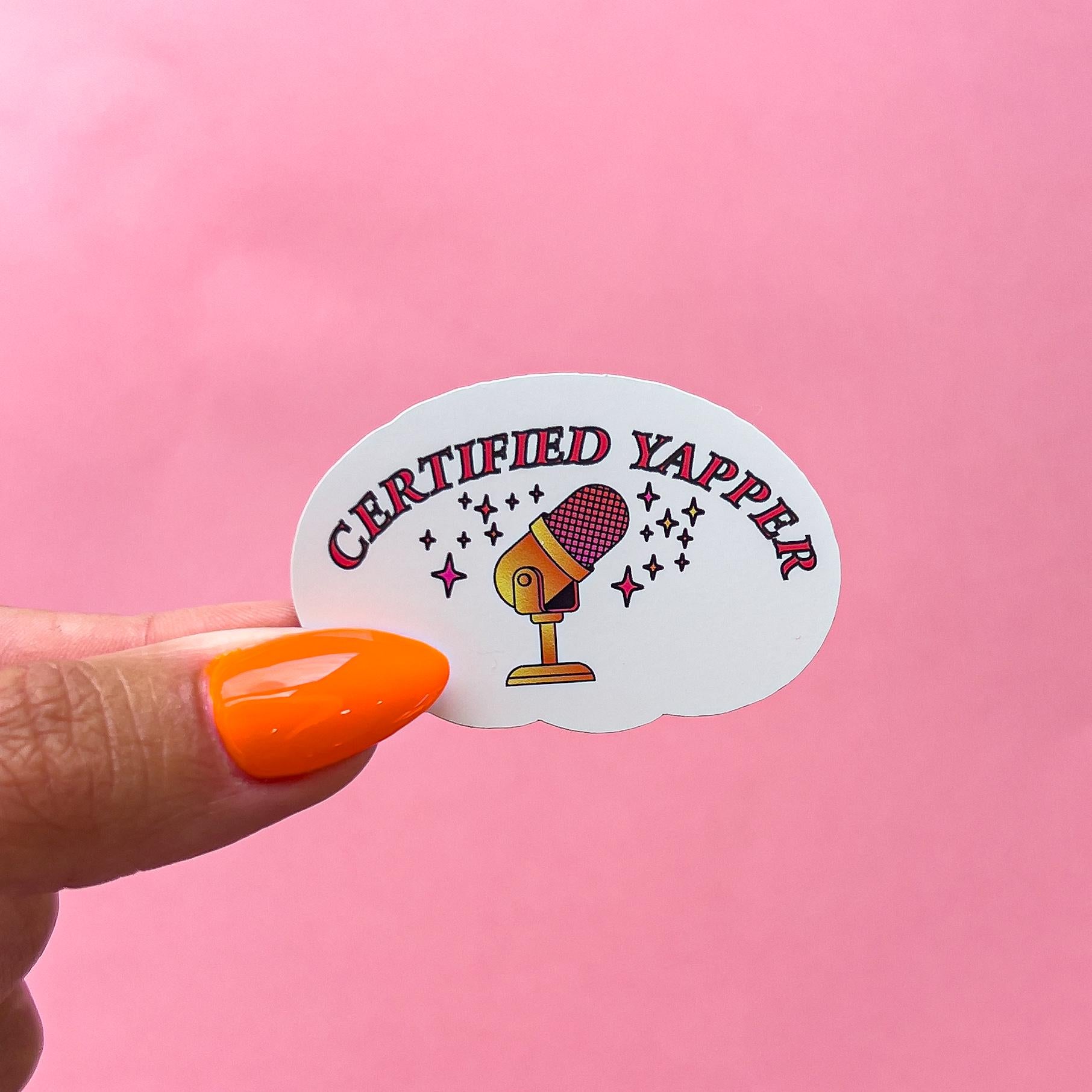 A vinyl decal sticker of a pink and gold microphone with stars around. The words 'CERTIFIED YAPPER' in pink are at the top.