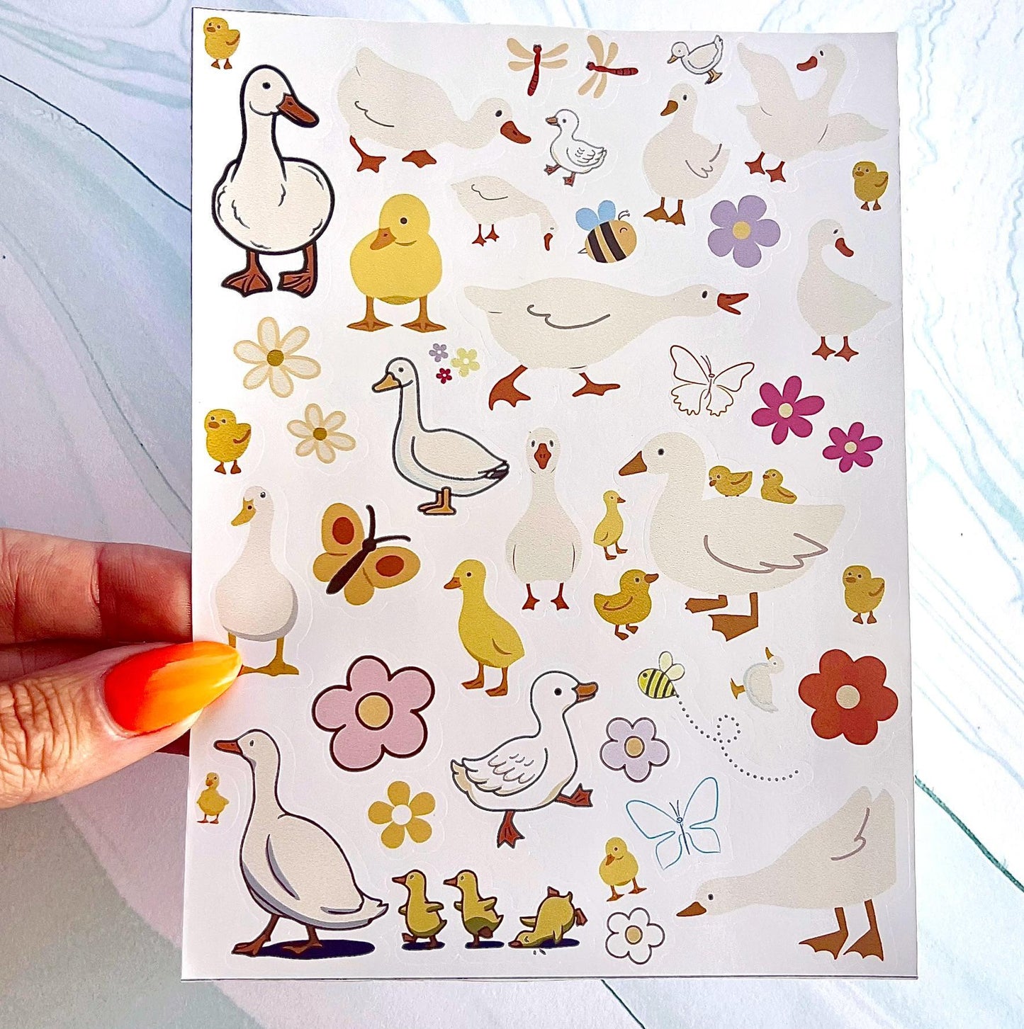A sheet of stickers with various images of ducks, flowers, bees, and butterflies. The ducks are white with orange beaks and feet. The flowers are pink, yellow, and orange. The bees are yellow and black. The butterflies are yellow, orange, and black.