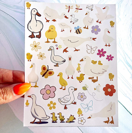 A sheet of stickers with various images of ducks, flowers, bees, and butterflies. The ducks are white with orange beaks and feet. The flowers are pink, yellow, and orange. The bees are yellow and black. The butterflies are yellow, orange, and black.