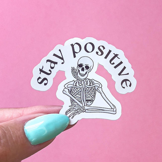 A vinyl decal sticker with a black and white skeleton and the text 'stay positive' is curved at the top.