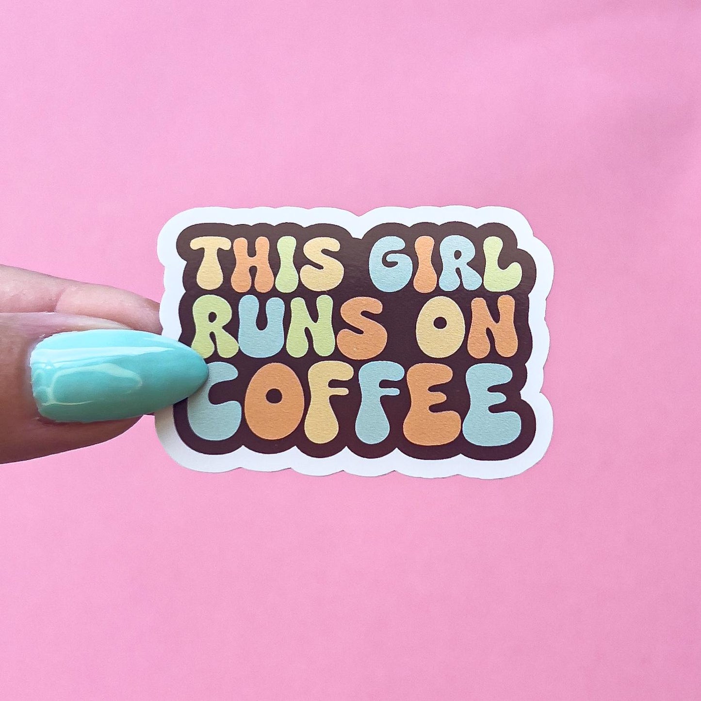 A vinyl decal sticker with the text 'This Girl Runs On Coffee' in colorful, bubbly letters. The letters are in shades of orange, yellow, green, and blue. The words are outlined in brown.