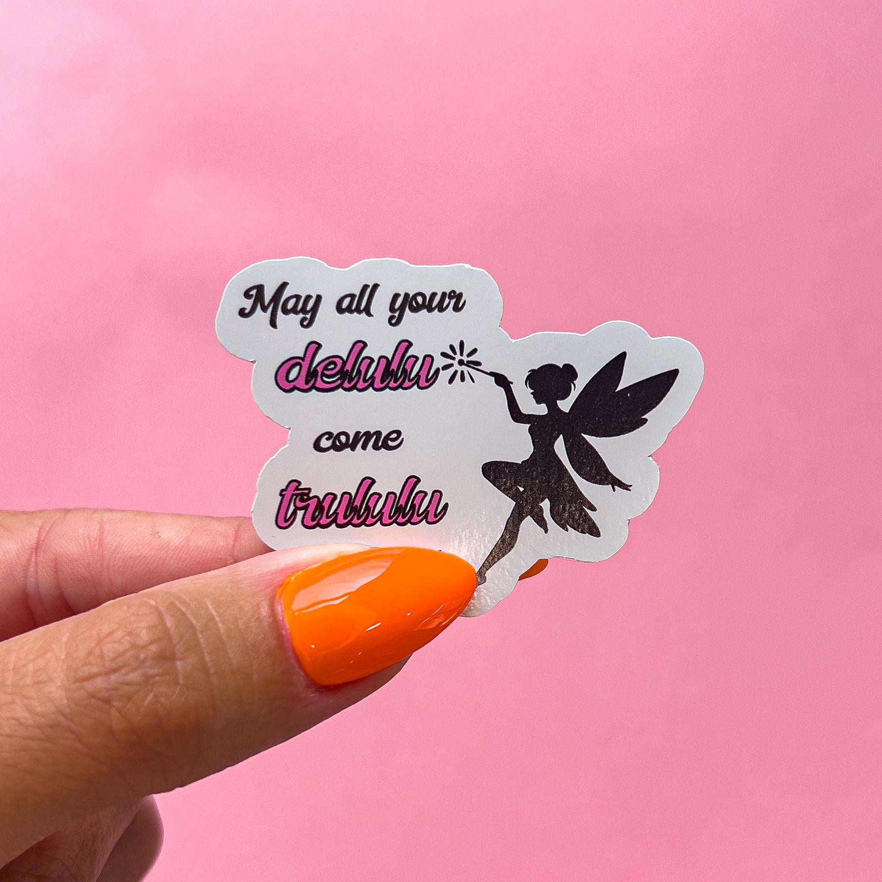A vinyl decal sticker of a black fairy silhouette holding a wand. The sticker has the text 'May all your delulu come trululu' in black and pink text.
