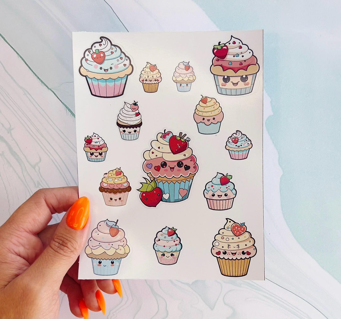 A sheet of cupcake stickers with various designs. The stickers are colorful and feature cupcakes with different frosting colors, sprinkles, and faces. Some cupcakes have strawberries on top. The stickers are perfect for decorating planners, laptops, water bottles, and other items.