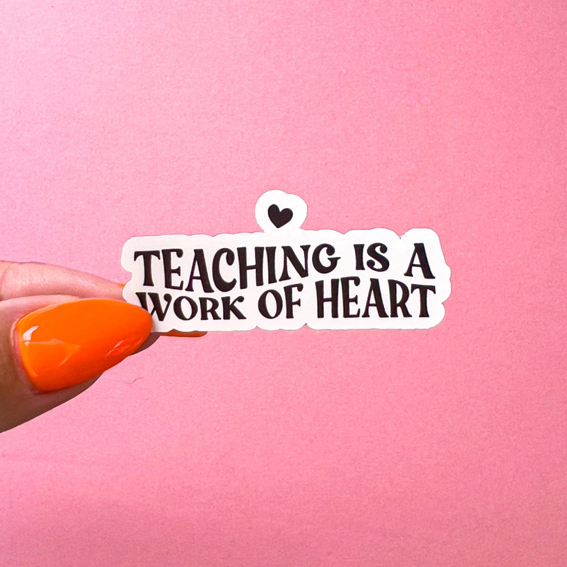A vinyl decal sticker with the words 'TEACHING IS A WORK OF ART' in wavy font and a heart at the top.