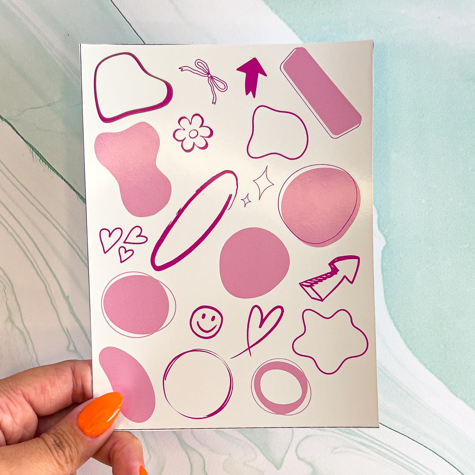 A sheet of various abstract shaped pink planner/notebook stickers. The stickers include hearts, arrows, flowers, circles, wavy circles, and rectangles. These can be used to keep track of important dates or tasks.