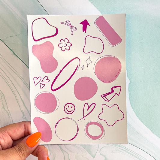 A sheet of various abstract shaped pink planner/notebook stickers. The stickers include hearts, arrows, flowers, circles, wavy circles, and rectangles. These can be used to keep track of important dates or tasks.