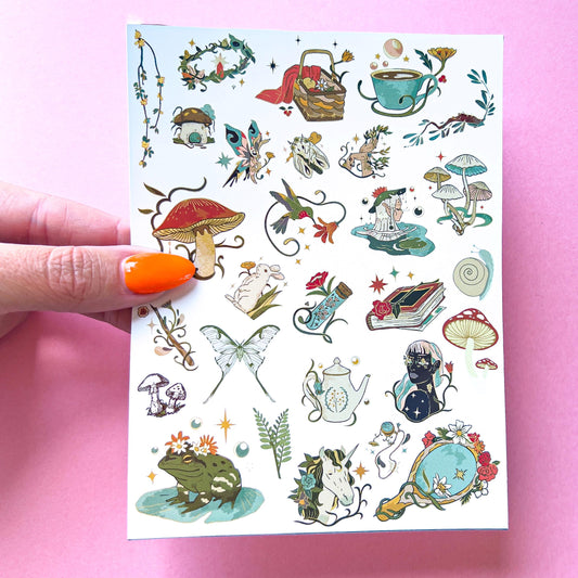 A sheet of stickers of illustrations including a mushroom, a butterfly, a frog, a unicorn, a teapot, a book, a mirror, a hummingbird, a rabbit, a snail, a fairy, a flower, a teacup, a wreath, a basket, a wand, a star, and a crescent moon. The stickers are ethereal and feature red, green, blue, and gold colors.