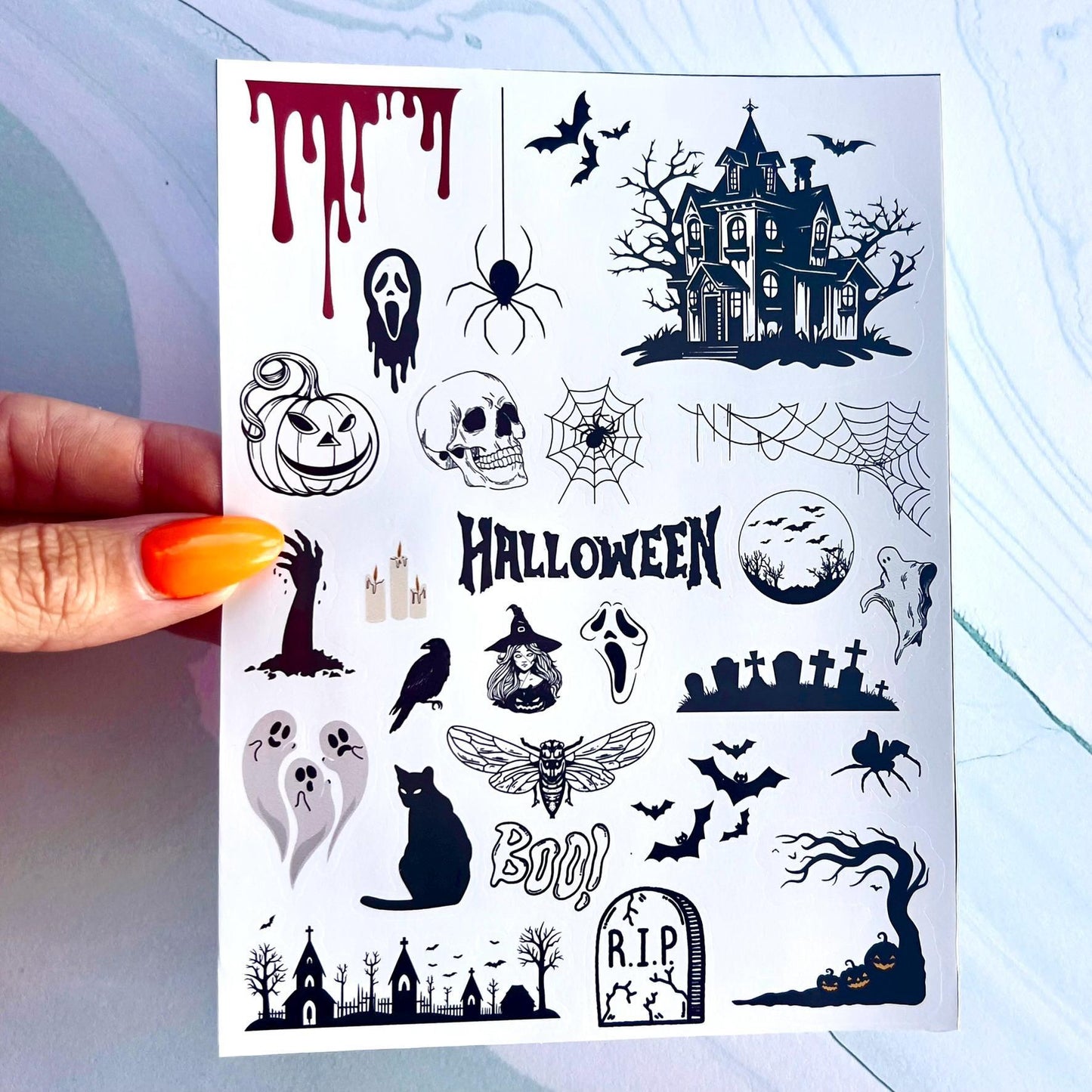 A sheet of Halloween themed stickers.The stickers include a haunted house, a pumpkin, a skull, a spider, a ghost, a witch, a bat, a graveyard, a crow, ghosts, a cat, a church, dripping blood, a hand coming out of the ground, and the words 'Halloween' and 'Boo!' ect.