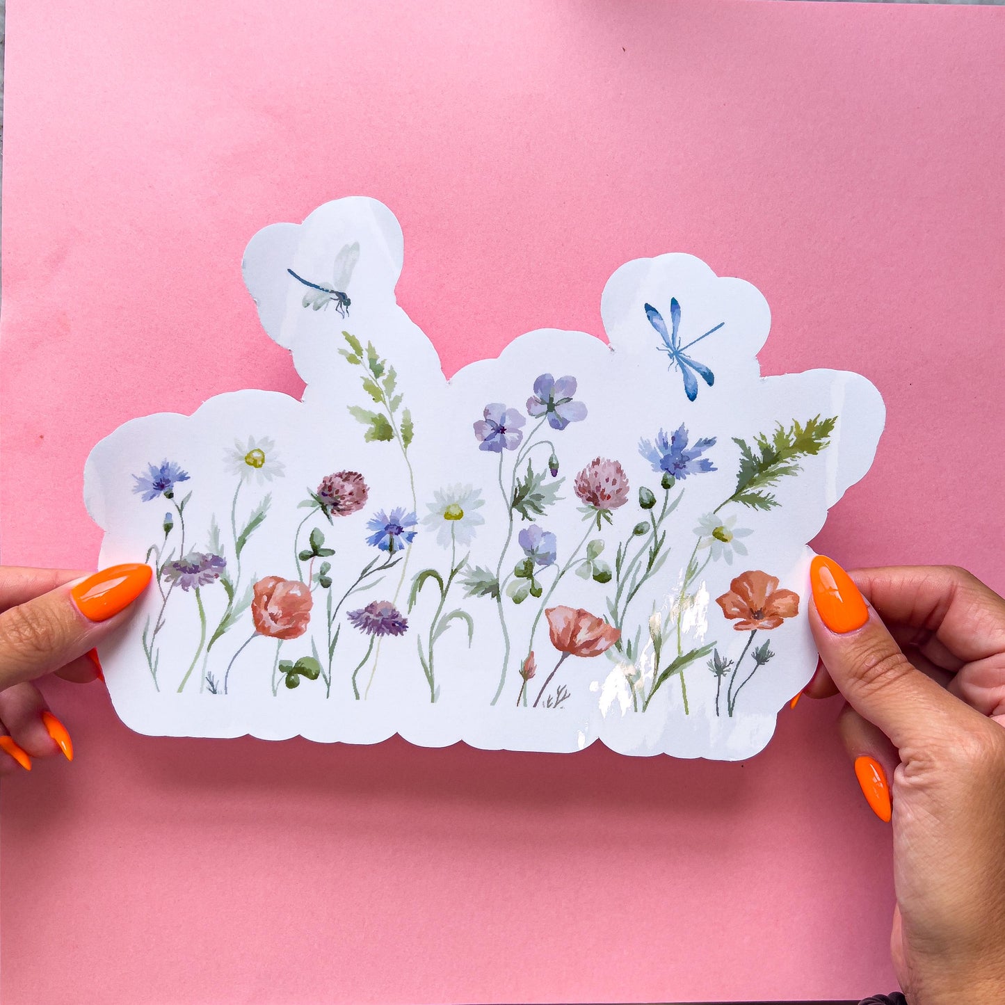 A vinyl decal sticker colorful wildflower border on clear vinyl. Includes purple, yellow, pink, red, and green colors. It has two blue dragonflies at the top flying around the flowers.