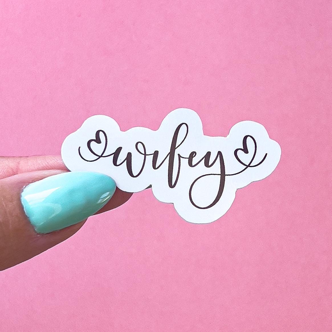 A vinyl decal sticker with the word 'wifey' written in cursive with a heart on each side of the word.