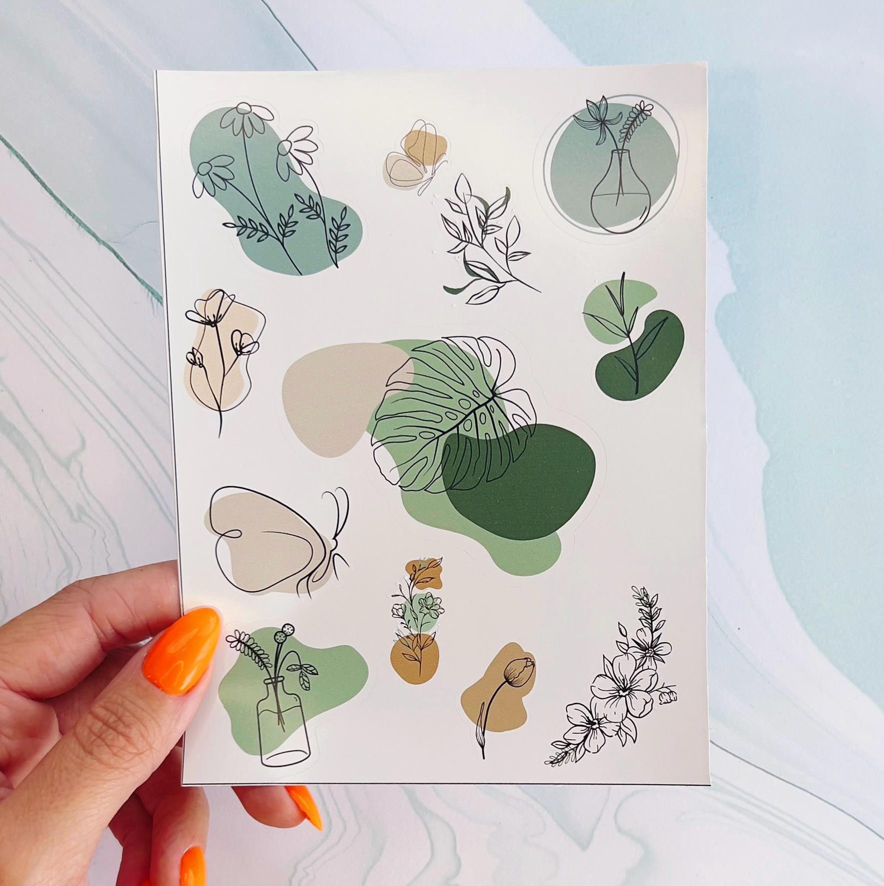 A sheet of minimalist floral and butterfly line drawn stickers. The stickers are line drawings of flowers, butterflies, and leaves with abstract shapes behind the line drawings. The abstract shapes are blue, green, and beige.