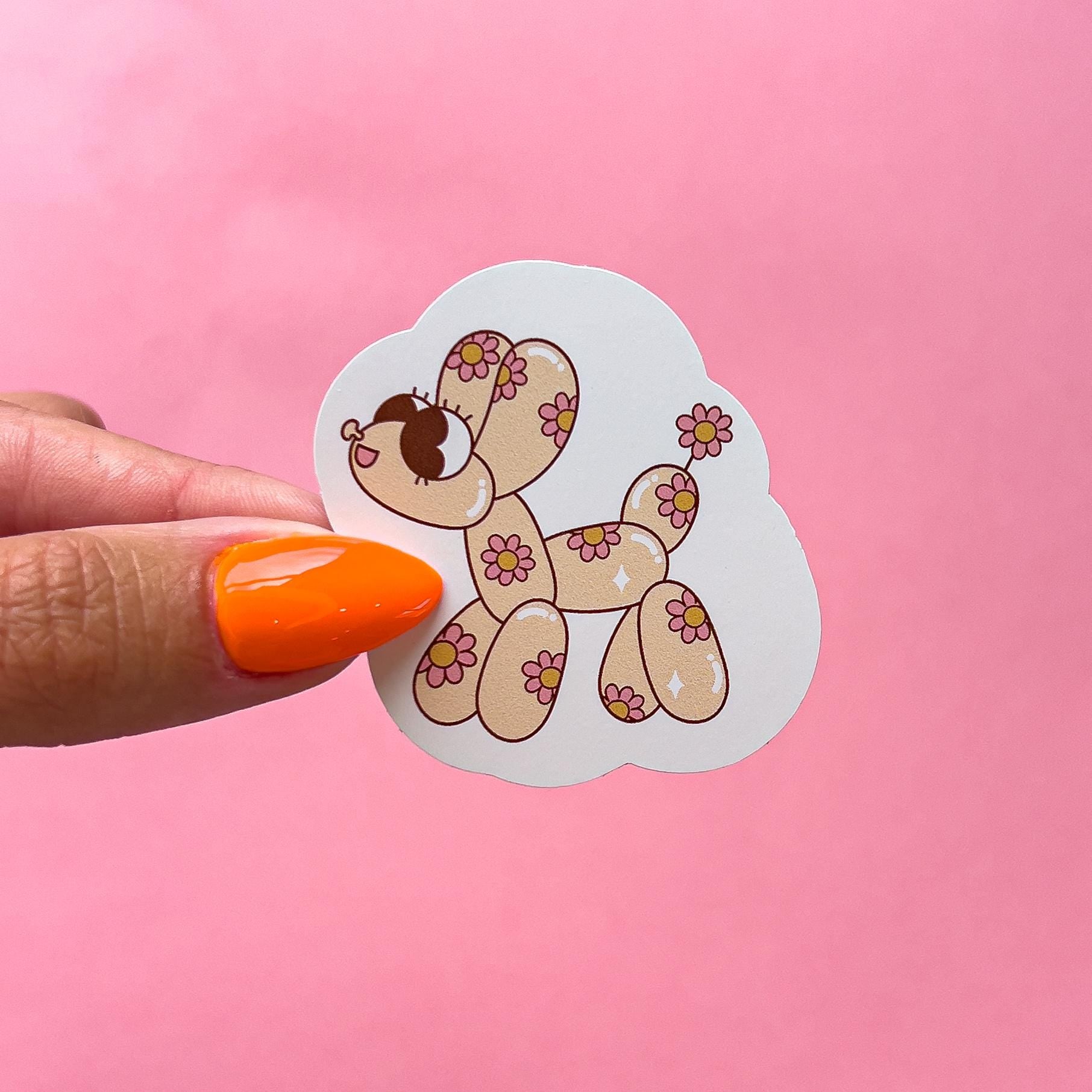 A sticker of a beige cartoon balloon dog with pink flowers on it.
